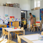 Patrizia taps into growing ’RE-Infra’ opportunity with €900m loan Primary school students coming into an art classroom at school. The teacher is welcoming them in.